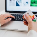 Close-up of hands using a laptop and holding a credit card for an online transaction.